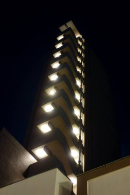 Şehrin modern mimarisinin gökdelenleri gecenin karanlığında yükseliyor.