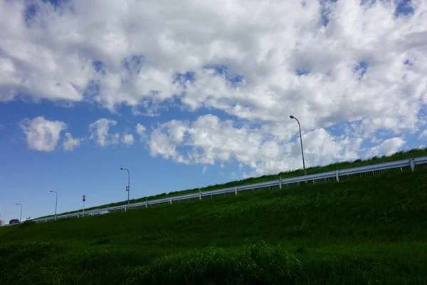 夏の空の落書きは 灼熱の青空の下で草を見上げ 尾根の上の夏の雲 — ストック写真