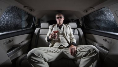 Beyaz takım elbiseli zengin bir adam ve arabada bir puro, bir limuzin.