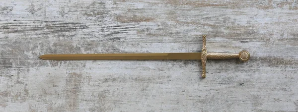 Schwert Mit Goldener Klinge Auf Weißem Holzgrund — Stockfoto