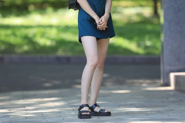 beautiful legs of a girl in a blue skirt in the park