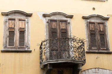 Garda Gölü kıyısındaki Riva del Garda 'da bir evin demir parmaklıkları ve tahta panjurları olan eski bir balkon.
