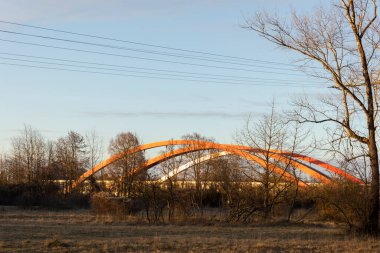 Augsburg yakınlarındaki Lech nehri üzerindeki karayolu köprüsünün kıvrımlı kırmızı kemerleri akşam güneşinin ışığında