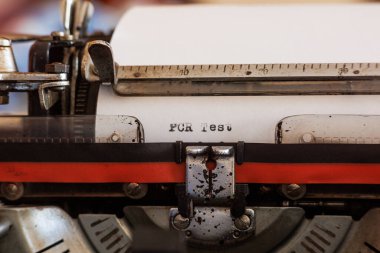 Almanca PCR Testi, kırmızı ve siyah kurdeleli eski bir daktilo kullanarak beyaz bir kağıt üzerine siyah mürekkeple yazılmış.