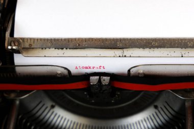 Almanca Atomkraft kelimesi eski bir mekanik daktiloda kırmızı ile yazılmış Almanca metin: Nükleer güç
