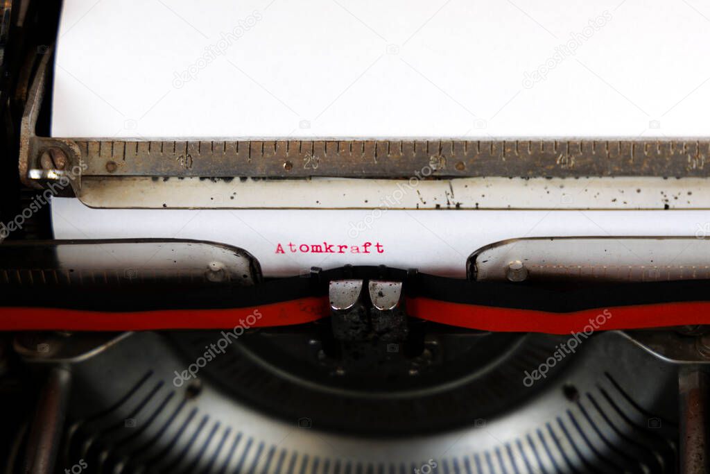 The German word Atomkraft written in red on an old mechanical typewriter German Text: Nuclear power