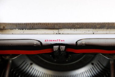 Almanca Atomwaffen kelimesi eski bir mekanik daktiloda kırmızı ile yazılmış: Nükleer Silahlar