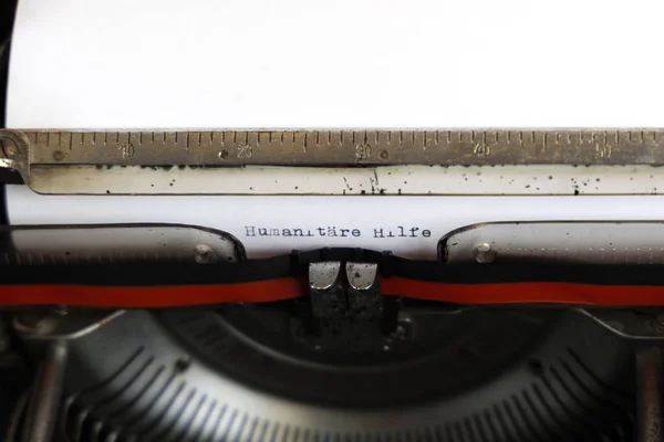 德语单词Humanitre Hilfe用红色写在一台旧的机械打字机上 — 图库照片