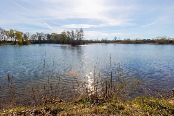 Güneş küçük bir gölün su yüzeyinde mavi gökyüzüne küçük yıldızlar şeklinde yansıyor.