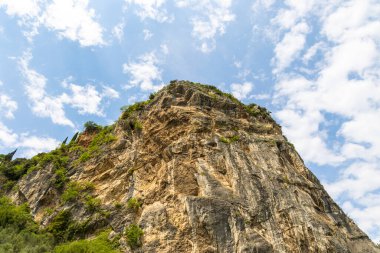 İtalya 'daki Garda Gölü yakınlarındaki kayalık dağlar mavi gökyüzü ve açık beyaz bulutlarla