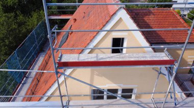 Bir çatı ustası tarafından tamir edilirken düz fayansları olan eski bir çatı.