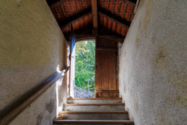 Staircase in an old masonry to a half-opened door into the light At the Loreto Chapel in Bhl am Alpsee near Immenstadt.