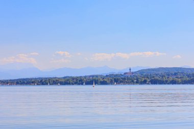View over Ammersee lake in Bavaria with sailboats on the water and Ammergau Alps in the background