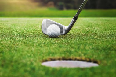 Golf oyuncusu golf topunu deliğe sokuyor