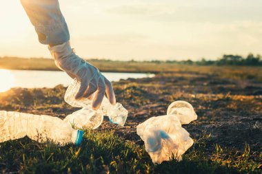 woman hand picking up garbage plastic bottle for cleaning at park