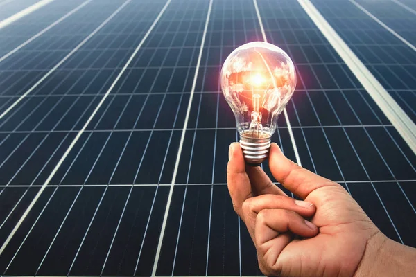 hand holding light bulb with solar panel background