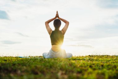 Kadın Yoga nehir doğası yakınında oturuyor.