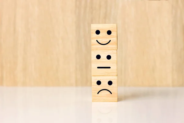 Smiley face happy and sad symbol on wooden block