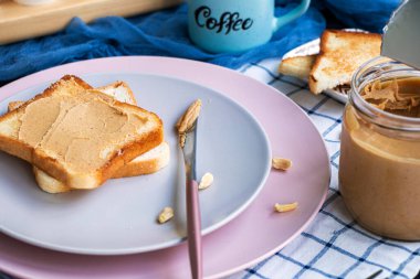 Bir dilim ekmek üzerinde kremalı fıstık ezmesi olan bıçak. Bir kavanoz dolusu fıstık ezmesi.