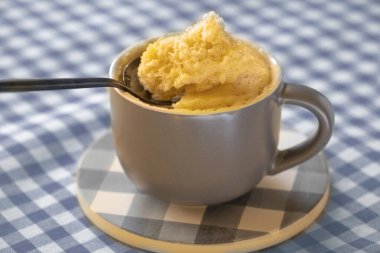 Kupada kek. Tatlı. Mikrodalgada pişmiş vanilyalı tatlı. Kek kupası. Kolay, pişirmesi hızlı. Kaşıkta vanilyalı bisküvi. Muz aromalı mugcake 'e yakın çekim. Ev yapımı kek tarifi. Kahvaltı.