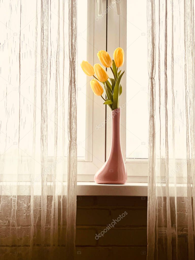 yellow tulips on the windowsill. Tulips comp Strong Gold in a vase