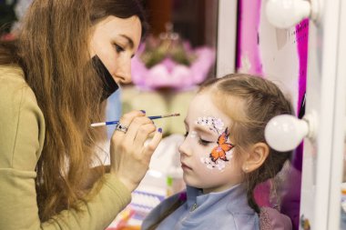 Çocuklar makyaj yüzlerini boyarlar. Kızlar resim yapar.
