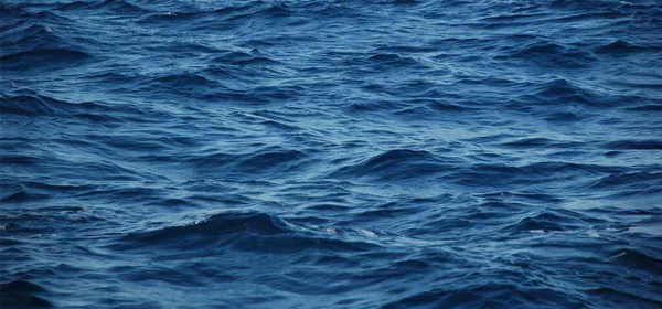 Olas de color azul oscuro, textura de agua azul. color azul oscuro profundo. Fondo de agua de mar — Foto de Stock