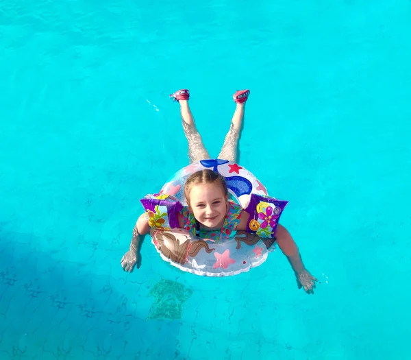 다채 로운 색깔의 울긋불긋 한 반지를 끼고 수영장에서 고무줄을 매고 있는 어린이. — 스톡 사진