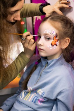 Çocuklar makyaj yüzlerini boyarlar. Kızlar resim yapar.