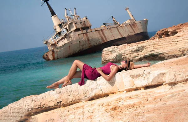 Een jonge vrouw ligt op een rots tegen de achtergrond van het verlaten schip Edro III — Stockfoto
