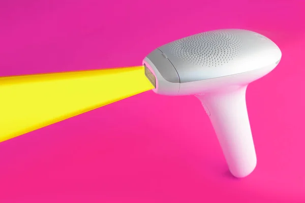 home modern laser epilator. Hair Remover offering Permanently Smooth Skin. Flash Epilator Laser isolate on a pink background. Female blog concept. Photoepilator for home use. selective focus.