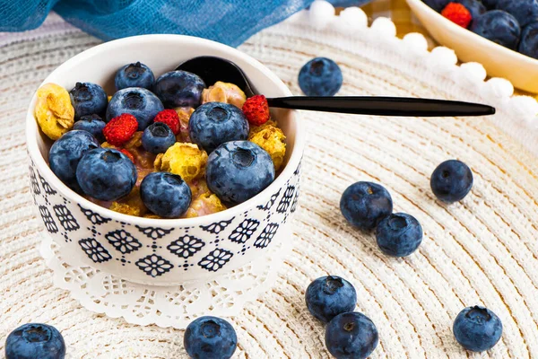 Bowl of homemade crispy granola with yogurt, fresh blueberry, fresh berries. healthy cereal morning breakfast. Oatmeal porridge with fresh blueberries, raspberries. fitness breakfast. crunches.