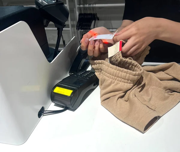 buying clothes. label scanning. cashier scans the barcode on the clothes in the store. Woman cashier, seller scanning and reading barcode from clothes using barcode scanner in female clothing store
