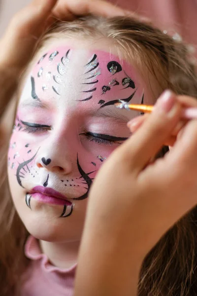 childrens makeup face paint drawings Girls face painting. Little girl having face painted on birthday party. closed eyes. High quality photo