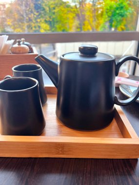 Çaydanlık siyah fincanı geleneksel çay seti Asya tarzı tasarım. Çay zamanı. Bir restoranda çay içmek, pencerenin dışında bir sonbahar manzarasıdır. modern siyah porselen çaydanlık. 