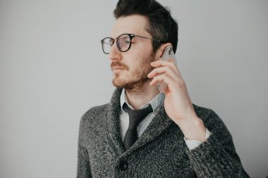 Sakallı, gözlüklü, gömlekli ve gri hırkalı genç bir adam...