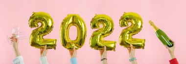 - Mutlu yıllar. Pembe arka planda birkaç el 2022 numarayı tutuyor. Boşluğu kopyala.