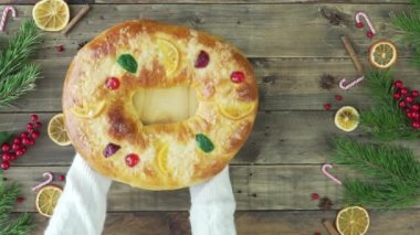 Kadınların elleri panettone ve Three Kings 'i Noel süslemeli ahşap bir masaya koyuyor. Noel yemeği kavramı.