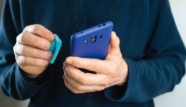 Cep telefonunu temizleyen adam. Virüsle sağlık önleme. Coronavirus. Covid 19.