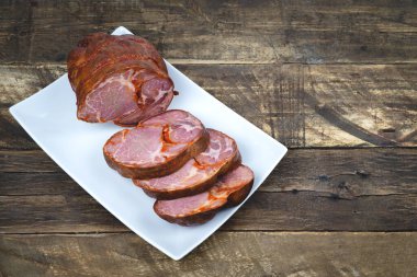 Chosco, siyah ahşap arka planda beyaz bir tabakta dilimlenmiş. Uzayı kopyala Dilimlenmiş sosis..