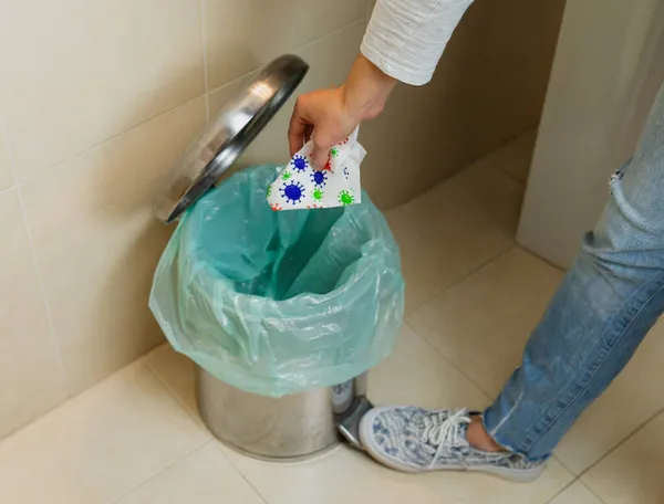 Çöp kutusuna virüslü mendil atan kadın. Coronavirus konsepti. COVID-19.