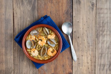 Ahşap arka planda karides ve deniz tarağı güvecinde yeşil fasulye. Uzayı kopyala en üstteki görünüm.