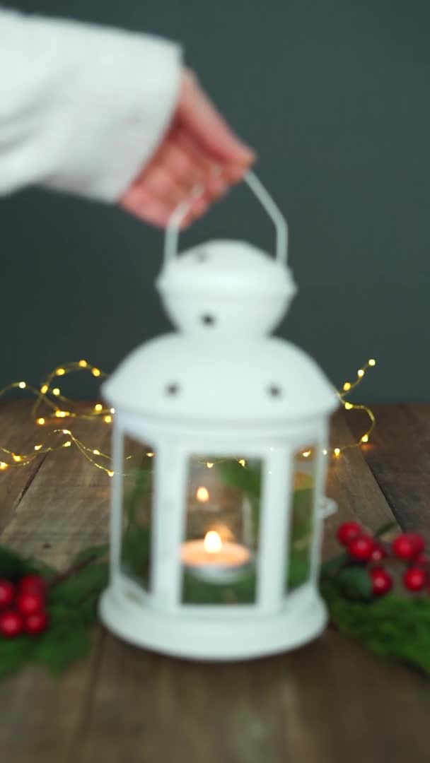 Ręczne umieszczanie latarni z zapaloną świecą i dekoracji świątecznej ze światłami w tle. Progresywna rozmycie. Pionowe wideo. — Wideo stockowe