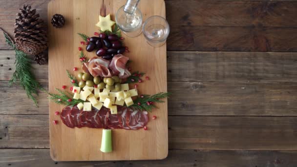 Tafel met voedsel in de vorm van een kerstboom en meerdere handen die voedsel oprapen en een andere die witte wijn schenkt. Horizontale video. — Stockvideo