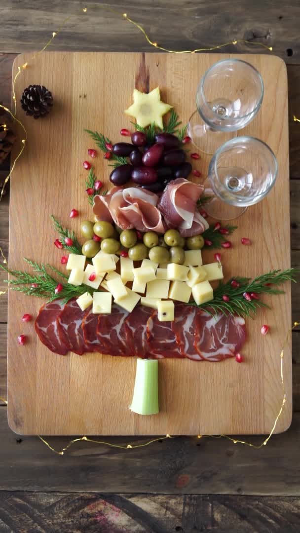 Tisch mit Essen in Form eines Weihnachtsbaums und mehreren Händen, die Essen nehmen, und einer, der Wein ausschenkt. Vertikales Video. — Stockvideo