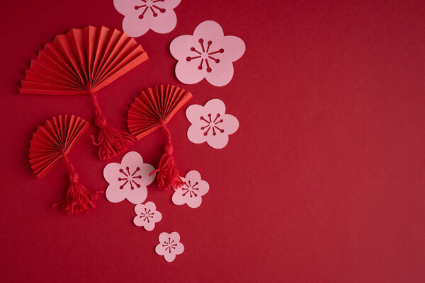 Китайский Новый Год. Украшение с традиционными китайскими новогодними мотивами, вырезать бумажные украшения на красном картонном фоне. Копирование пространства.