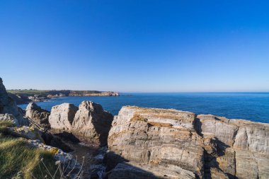 Kıyı manzarası, kayalar ve sakin mavi deniz. Boşluğu kopyala.