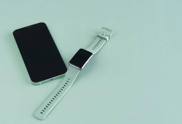 Yeşil arkaplanda yeşil akıllı saat ve telefon var. Uzayı kopyala Üst görünüm.
