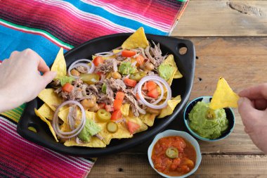 Eller, bir tepsi etli nacho 'dan yiyecek alıyor. Salsa soslu kâseler. Uzayı kopyala Meksika mutfak konsepti.