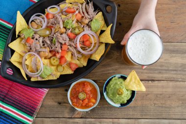 Bir tepsi nachos et ve bir bardak biraya tutunarak. Salsa soslu kâseler. Üst Manzara. Boşluğu kopyala.